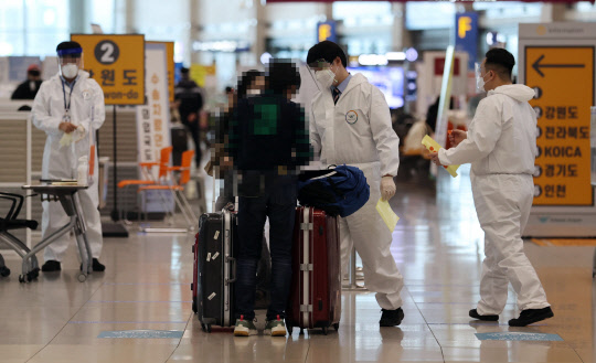 코로나19 확산세가 계속되는 27일 인천국제공항 제1터미널 입국장에서 방역 관계자들이 입국자들에게 동선을 안내하고 있다.   연합뉴스